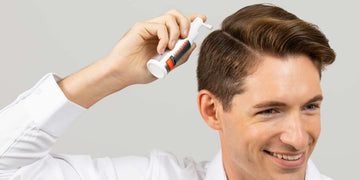 一名男性用喷雾涂抹器将FOLIGAIN外用护理产品涂在头皮上。