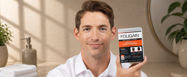 一名男性手持含5%米諾地爾和5% TRIOXIDIL的FOLIGAIN進階毛髮再生護理產品。