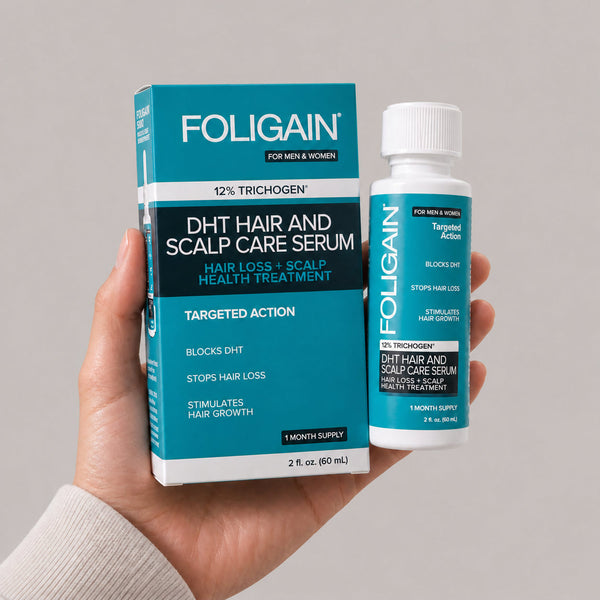 一隻手拿著FOLIGAIN DHT頭髮與頭皮護理精華液60 mL瓶及包裝盒。
